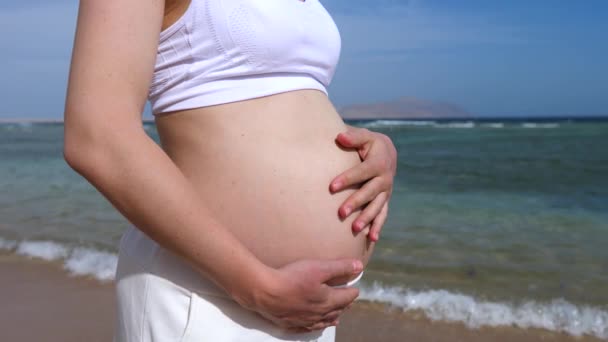 Donna incinta che si rilassa sulla spiaggia vicino al mare . — Video Stock