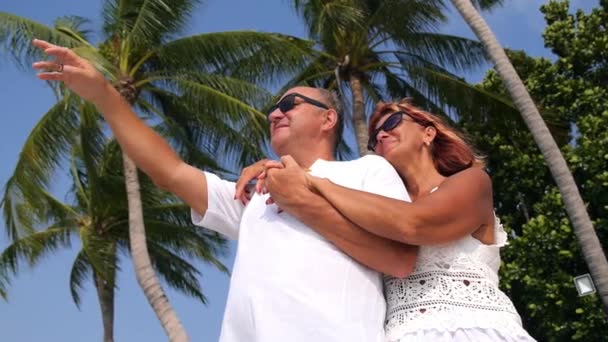 Senioren-Paar amüsiert sich am Strand vor Palmen. — Stockvideo