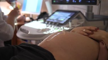 Tıbbi klinikte ultrason taraması yapan hamile bir kadının yakın çekimi.