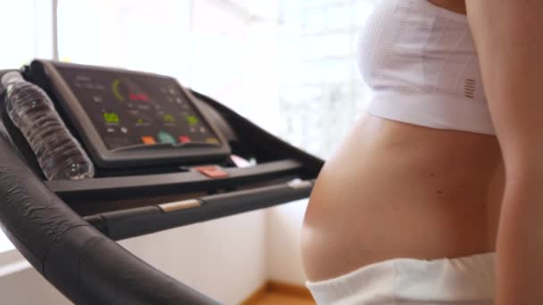 Těhotná žena na běžeckém pásu v tělocvičně — Stock video