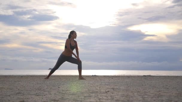 Fitness vrouw doet stretching benen oefening voor het lopen op het strand — Stockvideo