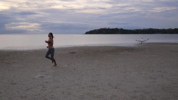 Flying Drone schieten een atletische sport vrouw lopen op het strand — Stockvideo