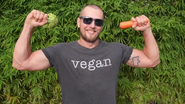 Fitness Veganistische sportman met verse groenten en een glimlach in de buitenlucht — Stockvideo