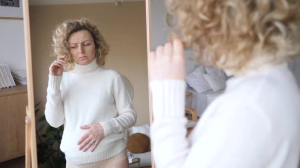 Verärgerte Schwangere mit Haarproblemen während der Schwangerschaft im Spiegel. — Stockvideo