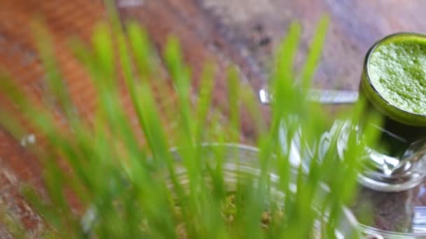 Jus d'herbe de blé en verre tourné sur une table en bois — Video