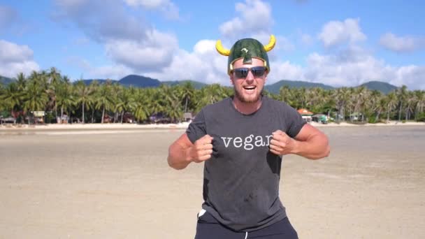 Смешной сердитый викинг в веганской футболке Ловля фруктов на пляже — стоковое видео