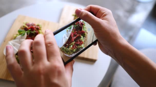 Las manos de la mujer tomando fotos de tostadas de aguacate con Smartphone — Vídeo de stock