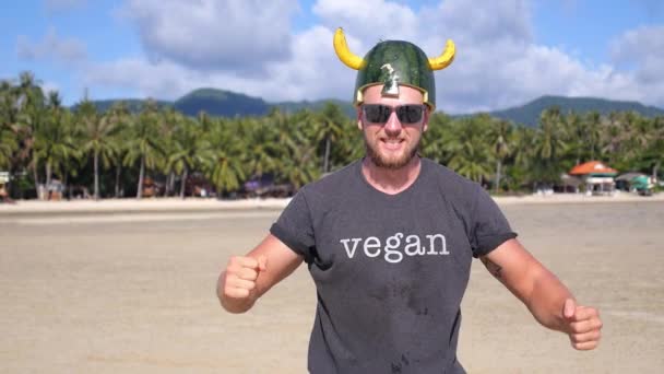 Grappige video met een knappe sportman die fruit vangt op het strand — Stockvideo