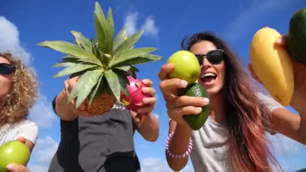 Группа молодых людей веселится с фруктами против голубого летнего неба — стоковое видео