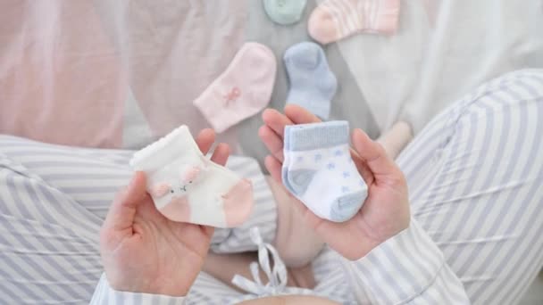 Schwangere hält Baby-Socken für einen Jungen und ein Mädchen. — Stockvideo