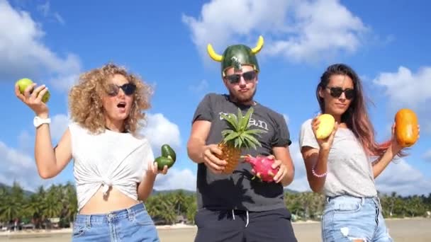 Amigos felices bailando juntos con frutas en la playa en verano — Vídeos de Stock
