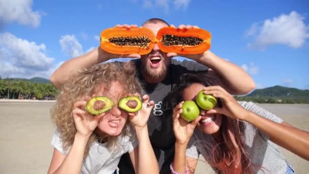 Jeunes gens heureux avec des yeux de fruits s'amusant sur la plage — Video