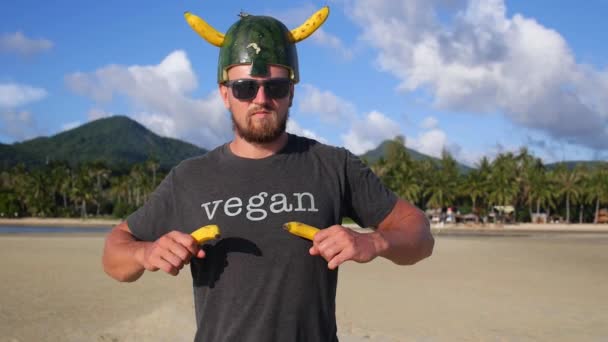 Muskularne brodatego człowieka wegańskie z bananami na plaży — Wideo stockowe