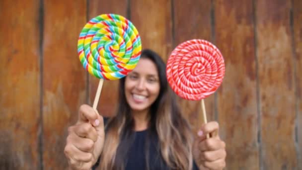 Jonge vrouw met lolly snoep op straat met houten achtergrond — Stockvideo