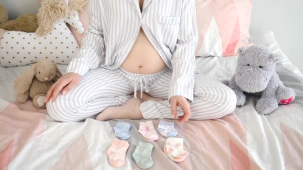 Zwangere vrouw op zoek naar kleine baby sokken in de kinderkamer. — Stockvideo