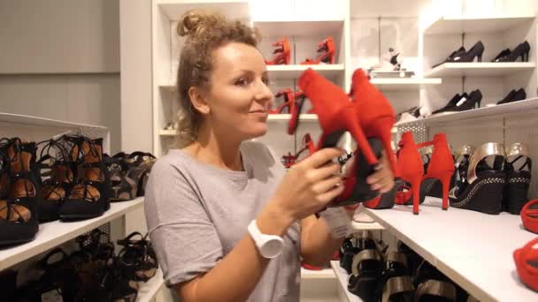 Счастливая женщина-шопоголик покупает обувь в обувном магазине — стоковое видео