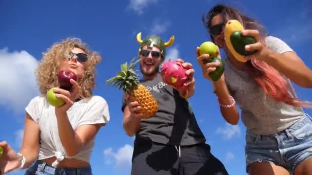 Молодые кузнечные друзья весело танцуют на пляже с фруктами . — стоковое видео