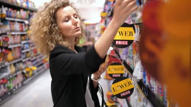 Mujer joven eligiendo un producto de cuidado personal en el supermercado — Vídeo de stock