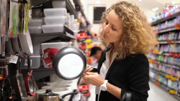 Mujer comprando en supermercado eligiendo sartén — Vídeos de Stock