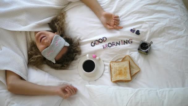 ผู้หญิงสาวนอนบนเตียงกับกาแฟในตอนเช้าขี้เกียจ — วีดีโอสต็อก