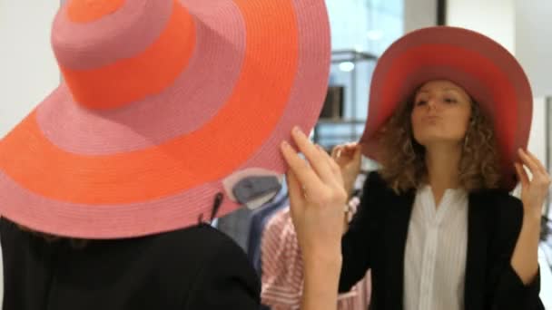 Femme essayant chapeau d'été dans la boutique de vêtements en face du miroir — Video