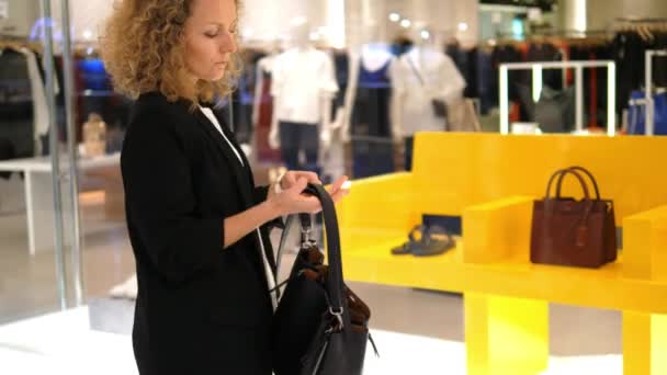 Jonge vrouw kiezen van een tas in het winkelcentrum — Stockvideo