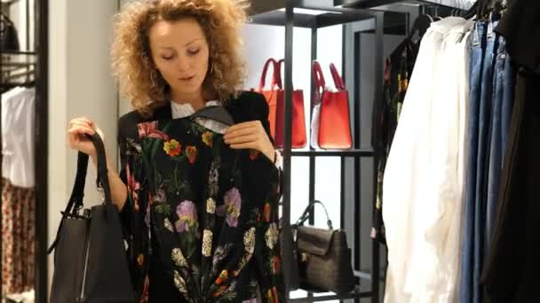 Młoda kobieta mody próbuje na ubrania w sklepie odzieżowym — Wideo stockowe