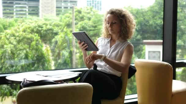 Joven empresaria usando tableta digital sentada en el café — Vídeo de stock