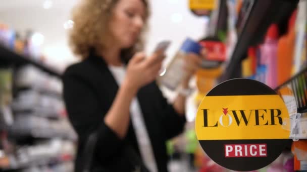 低価格でスーパーマーケットでスマートフォンショッピングを持つ女性サイン — ストック動画