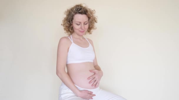 幸せな妊娠中の女性の肖像彼女の腹と笑顔に触れる — ストック動画