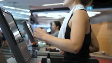 Spor salonunda koşu bandında egzersiz yapan genç bir kadın.