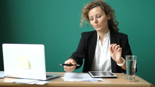 Zakenvrouw zit aan tafel in kantoor en werkt met laptop — Stockvideo