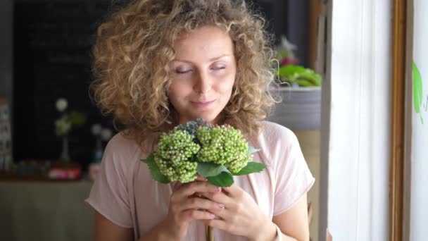 Mujer joven con flores mirando en la cámara — Vídeos de Stock