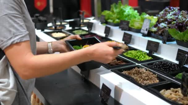 Concetto di alimentazione sana: donna che mette la quinoa in insalata al bar dell'insalata — Video Stock