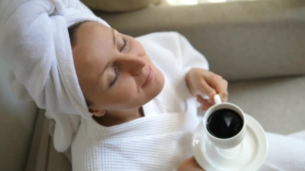 Glimlachende vrouw dragen badjas Genieten van een kopje koffie — Stockvideo