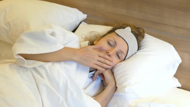 Zívající žena upadá spát v posteli — Stock video