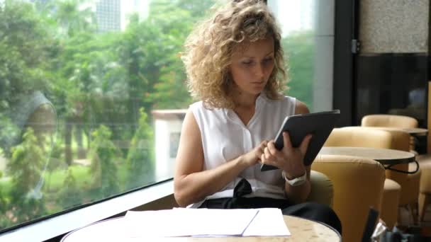 在咖啡店里使用数码平板电脑的年轻而严肃的女商人 — 图库视频影像