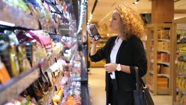 Mujer joven eligiendo productos en el supermercado — Vídeo de stock