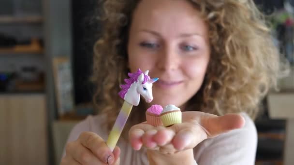 Милая молодая женщина, играющая с разноцветной ручкой единорога — стоковое видео