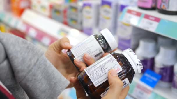 Mala mujer leyendo etiqueta en botella de la píldora en la farmacia — Vídeo de stock