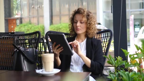 Joven mujer de negocios segura usando la tableta en el café — Vídeo de stock