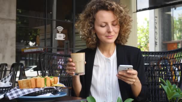 使用智能手机和喝咖啡的年轻女商人 — 图库视频影像