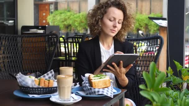 Pewny siebie Business Woman Korzystanie z tabletu podczas jedzenia śniadania — Wideo stockowe