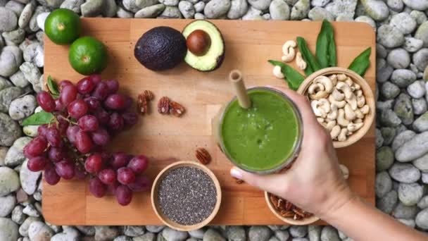 Top View van vrouwelijke hand met gezonde veganistische groene smoothie — Stockvideo