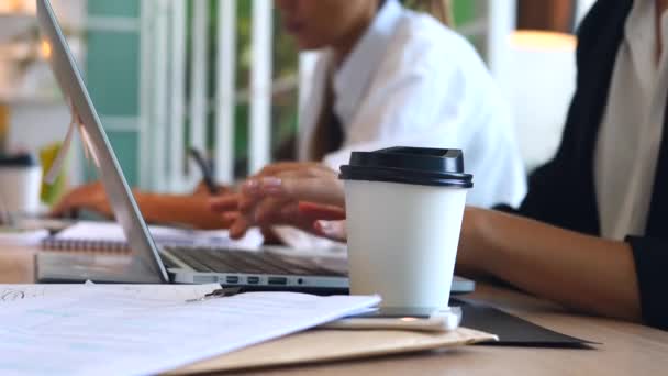 Γυναικεία χέρια πληκτρολογώντας σε φορητό υπολογιστή πίνοντας καφέ στο χώρο εργασίας — Αρχείο Βίντεο