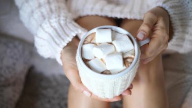Ellerinde örgü süveter olan kadın eli şekerlemeli sıcak çikolata.