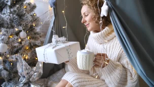 Mujer feliz sostiene chocolate caliente con malvaviscos y regalos de Navidad — Vídeo de stock