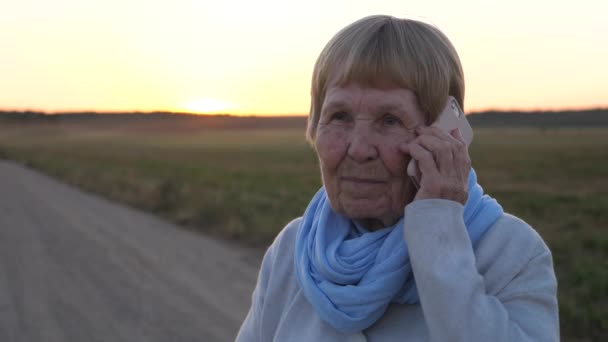 Mormor talar på mobilen utomhus på vägen — Stockvideo