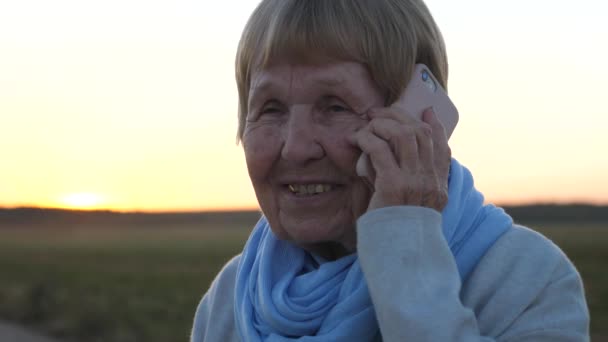 Mujer mayor hablando por teléfono al aire libre — Vídeos de Stock