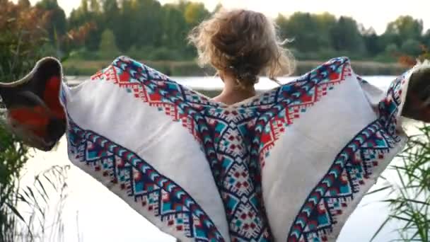 Relajante mujer joven en la naturaleza disfrutando de la vista del lago con poncho — Vídeos de Stock